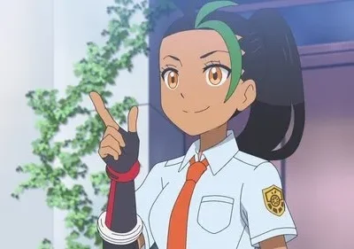 Anime: jovem morena sorrindo, cabelo preto c/ mechas verdes, camisa escolar, gravata laranja, luvas. Aponta p/ cima em fundo claro com plantas.