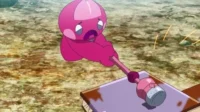 Criatura rosa de anime com expressão triste, batendo um martelo rosa numa tábua roxa. Faíscas no chão terroso.