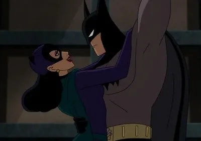 Um herói mascarado de capa preta e uma mulher de máscara felina roxa se encaram em um abraço intenso em ambiente escuro.