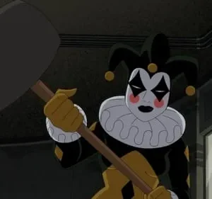 Arlequim de animação em preto e dourado, com rosto pintado e chapéu de três pontas, segura um martelo gigante. Fundo escuro.