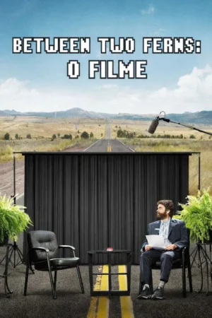 Homem barbudo de terno sentado em talk show improvisado numa estrada deserta. Microfone boom. Cenario absurdo e cômico.