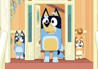 Um cachorro adulto azul e preto surpreso na porta, com dois filhotes, um curioso e outro tímido, espiando de trás.