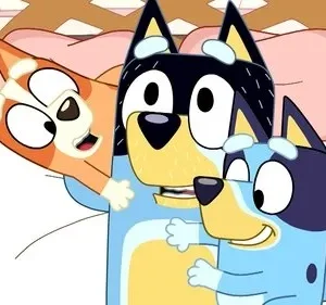 Três cães azuis e laranjas animados, um adulto e duas crianças, abraçando-se alegremente em uma cama.