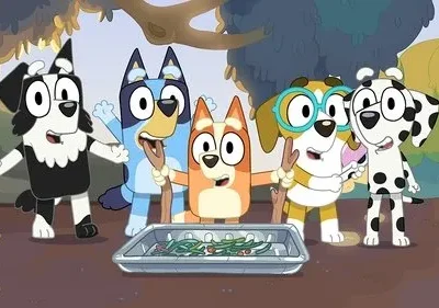Cinco cães animados, incluindo um dálmata e um border collie, brincam em um parque. Eles olham animados para um prato de vegetais.