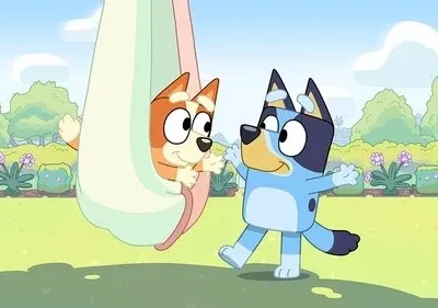 Cachorro laranja brinca numa rede com cachorro azul sorrindo em um parque. Cena alegre e divertida sob o sol.