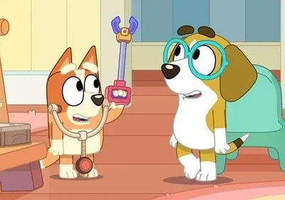 Cão laranja com estetoscópio e pinça de brinquedo brinca de médico com um beagle de óculos, que parece receoso. Ambiente alegre.