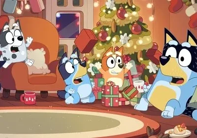 Quatro cães animados, dois adultos e dois filhotes, em uma sala de Natal caótica. Presentes voam, todos parecem surpresos e animados.