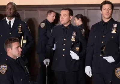 Grupo de policiais em uniformes azuis-escuros formais, com luvas brancas e chapéus na mão, em evento cerimonial.