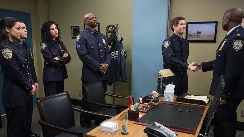 Brooklyn Nine-Nine:Lei e Desordem – T01E22:A demissão 1 Seis policiais em uniforme azul numa sala. Dois homens sorriem ao apertar as mãos,enquanto quatro colegas os observam.