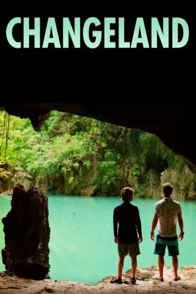 Dois homens de costas na saída de uma caverna escura, olhando um lago azul-turquesa cercado por folhagem tropical.