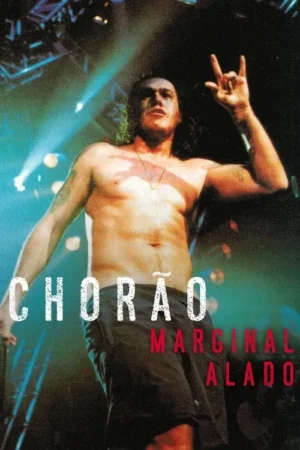 Homem sem camisa, cabelo comprido, com sinal de rock em palco iluminado por luzes azuis e vermelhas. Atmosfera de show de rock.