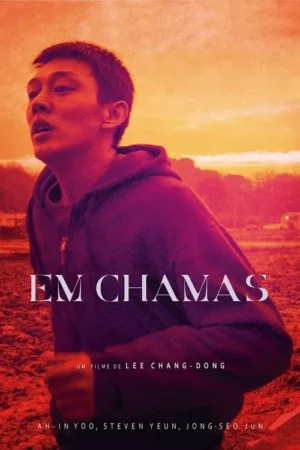 Homem em hoodie roxo sob céu vibrante de pôr do sol em tons de laranja e vermelho. Ele olha para cima com expressão intensa.