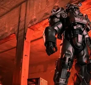 Personagem em armadura futurista cinza-escura impõe-se em ruínas de concreto, com brilho vermelho intenso e fogo ao fundo.