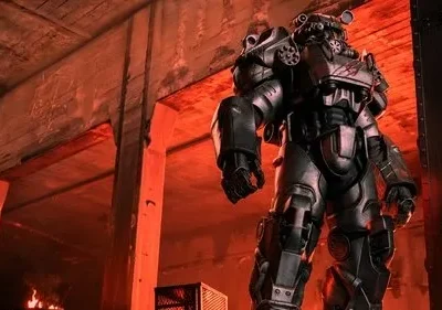 Personagem em armadura futurista cinza-escura impõe-se em ruínas de concreto, com brilho vermelho intenso e fogo ao fundo.
