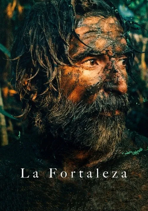 Close-up de homem sujo de lama,com barba e cabelo molhados,em floresta escura. Expressão intensa de sobrevivência.