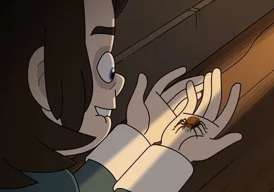 Jovem animado sorri, olhando uma aranha colorida nas suas mãos, iluminadas por um feixe de luz quente.