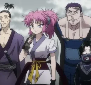 Quatro figuras de anime em pé. Homem com espada, mulher de cabelo rosa e microfone, homem corpulento e jovem mascarado de caveira. Fundo claro.