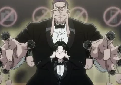 Homem imponente de terno com pontos no rosto e correntes nos dedos. Um jovem tapa os ouvidos à frente. Sinais de proibido no fundo. Clima misterioso.