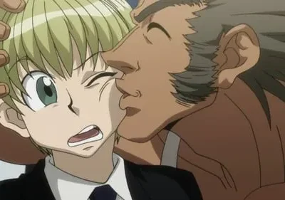 Homem de pele escura sorri beijando o rosto de um garoto loiro de terno, que reage com uma careta de surpresa e um olho fechado.