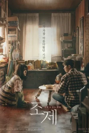 Mulher e homem sentados no chão de um quarto antigo e acolhedor, com luz suave. Clima íntimo e nostálgico.