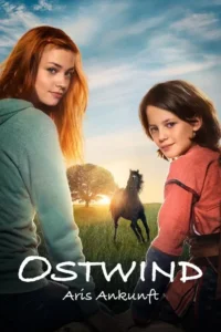 Uma jovem ruiva e uma criança sorriem em um campo verde. Um cavalo preto corre à direita,com árvore e sol ao fundo. Clima amigável.