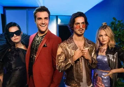 Quatro personagens com roupas estilosas de festa em um cenário noturno azulado. Um homem sorri, os outros têm expressões sérias.