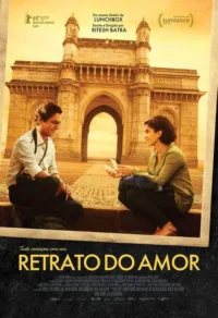 Um fotógrafo e uma mulher sorriem,sentados em degrau,trocando fotos,com um arco imponente dourado ao fundo. Clima romântico.