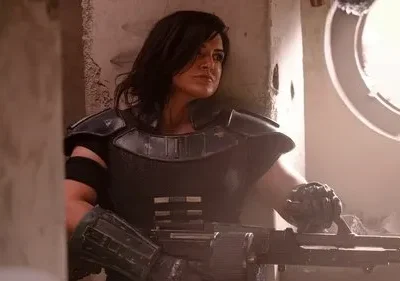 Mulher de cabelo escuro em armadura tática preta segura arma pesada. Olhar determinado num ambiente sombrio com janela redonda e fumaça.