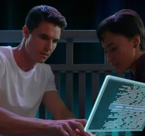 Homem e mulher concentrados em tablet holográfico com código, em cenário escuro e futurista.
