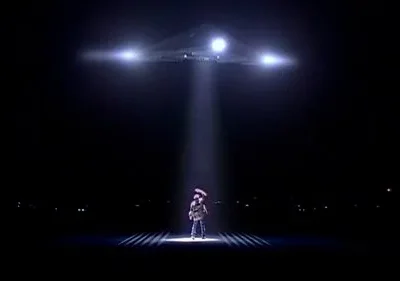 Noite escura. Nave triangular com luzes brilhantes irradia um feixe sobre figura de chapéu. Cena de suspense e mistério.