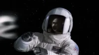 Um astronauta em traje branco flutua no espaço escuro. Um reflexo fantasmagórico no visor e uma névoa etérea pairam ao longe.