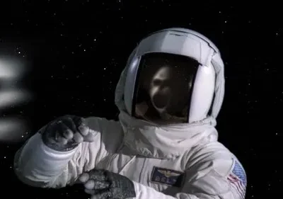 Um astronauta em traje branco flutua no espaço escuro. Um reflexo fantasmagórico no visor e uma névoa etérea pairam ao longe.