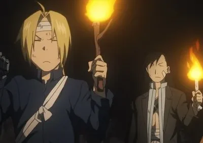 Edward Elric e Ling Yao de Fullmetal Alchemist em uma caverna escura, ambos segurando tochas com expressões sérias.