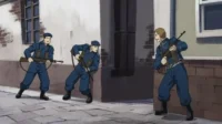 Fullmetal Alchemist:Três soldados Amestrinos,em uniformes azuis e armados,avançam cautelosamente por uma rua estreita. Clima tenso.