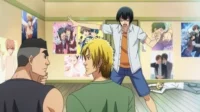 Iori de Grand Blue gesticula furioso em um quarto cheio de pôsteres BL. Outros rapazes, incluindo um caído, o observam. Cena cômica.