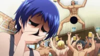 Jovem de Grand Blue chora, olhos escuros e marejados, enquanto homens nus festejam euforicamente com canecas de cerveja em uma cena caótica.