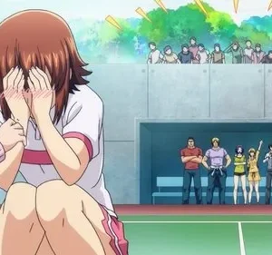 Em Grand Blue, Chisa, envergonhada, esconde o rosto enquanto Iori grita. Outros personagens e público assistem num campo esportivo.