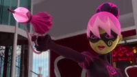 Vilã animada de pele verde-amarelada, cabelo rosa e máscara, em roupa roxa com detalhes rosa. Ela aponta uma arma de perfume rosa brilhante.