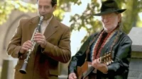 Monk (Tony Shalhoub) no clarinete e Willie Nelson no violão, tocando um dueto musical em cena da série Monk.