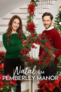 Um casal sorridente em suéteres natalinos segura uma guirlanda. Fundo festivo com escada decorada e árvore de Natal.