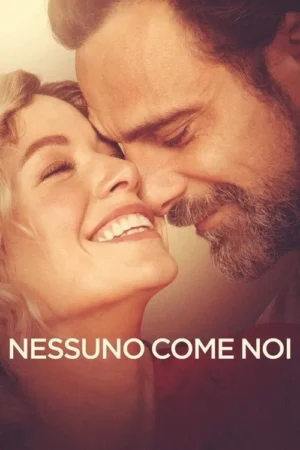 Close-up de casal: mulher loira sorrindo com olhos fechados, homem barbudo com rosto perto. Ambiente caloroso e romântico.