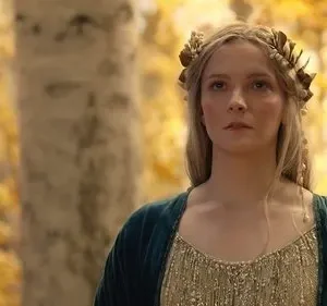 Galadriel de Os Anéis de Poder, loira com coroa de folhas douradas, olha séria em floresta outonal. Clima épico.