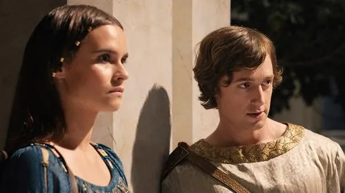 O Senhor dos Anéis:Os Anéis de Poder – T01E04:A Grande Onda 1 Em Os Anéis de Poder,Eärien de azul e Kemen de túnica com gola dourada trocam olhares pensativos. Cenário clássico.