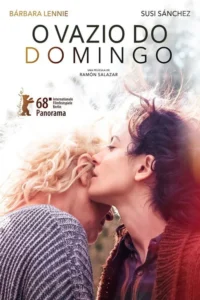 Duas mulheres,uma loira e uma morena,em abraço íntimo,com a morena se aproximando do rosto da loira. Fundo claro e suave.