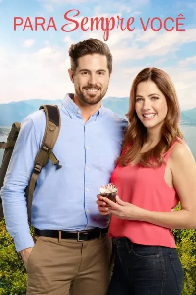 Jovem casal sorridente em paisagem montanhosa com lago. Ele de camisa azul e mochila, ela de blusa rosa com cupcake. Clima leve e romântico.