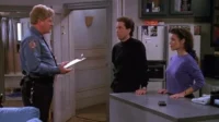 Em Seinfeld, um policial loiro com prancheta fala com Jerry e Elaine na cozinha. Eles parecem confusos.