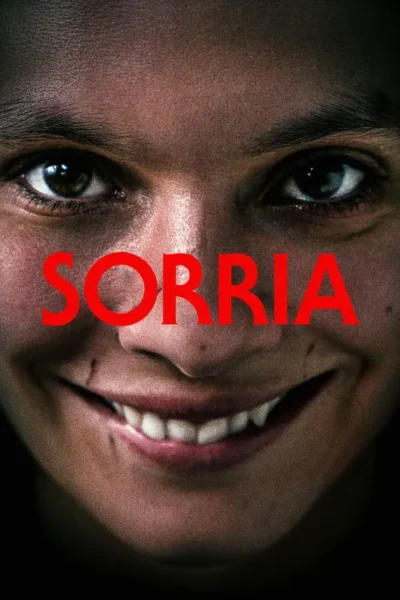 Close-up de rosto com sorriso forçado e olhos arregalados, transmitindo um terror inquietante. Dentes visíveis na boca escancarada.