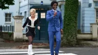 Doctor Who – T01E02:O Som do Diabo 9 Doctor Who:Casal retrô dos anos 60,homem de azul e mulher de preto/branco,cruzam a Abbey Road. TARDIS azul ao fundo.
