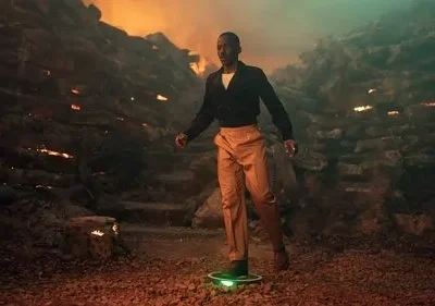 Homem elegante flutua em plataforma verde num cenário rochoso com fogo, exalando um clima de aventura sci-fi. Pôster de série/filme.