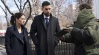 Os agentes do FBI Maggie e OA,apreensivos,observam um técnico em traje antibomba com um tablet em cena urbana.